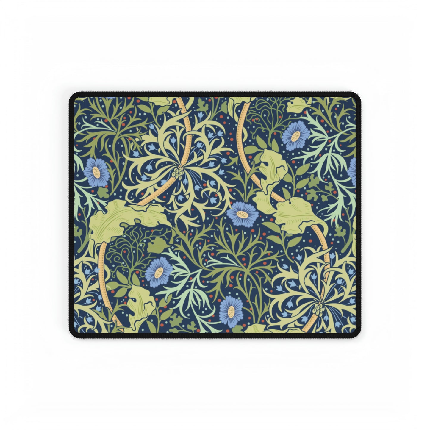 A large desk mat with a blue floral William Morris & Co pattern displayed under a monitor and accompanied by a keyboard and mouse.