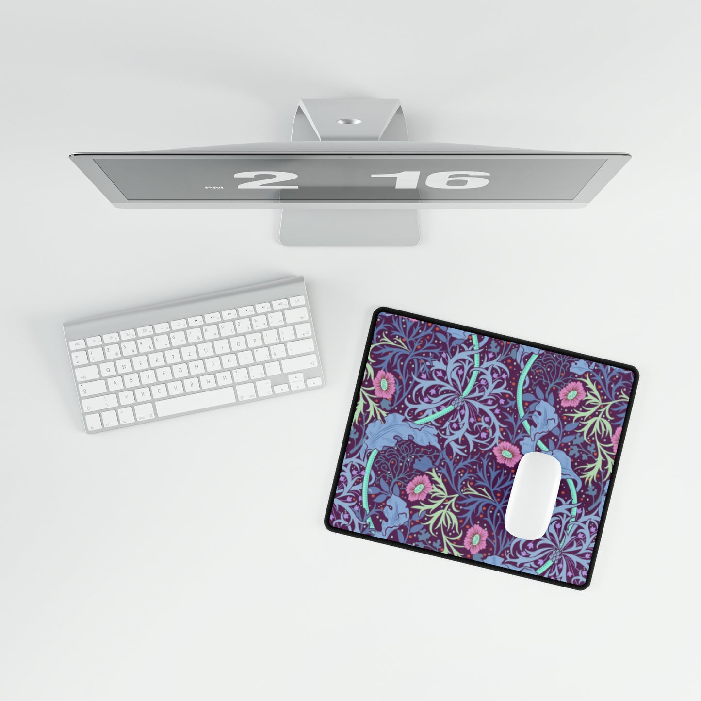 A large desk mat with a floral pattern, displayed on a desk with a keyboard and mouse, with a monitor above it.