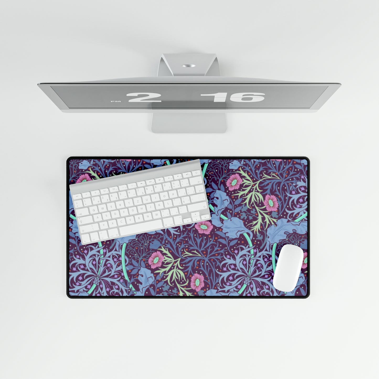 A large desk mat with a floral pattern, displayed on a desk with a keyboard and mouse, with a monitor above it.