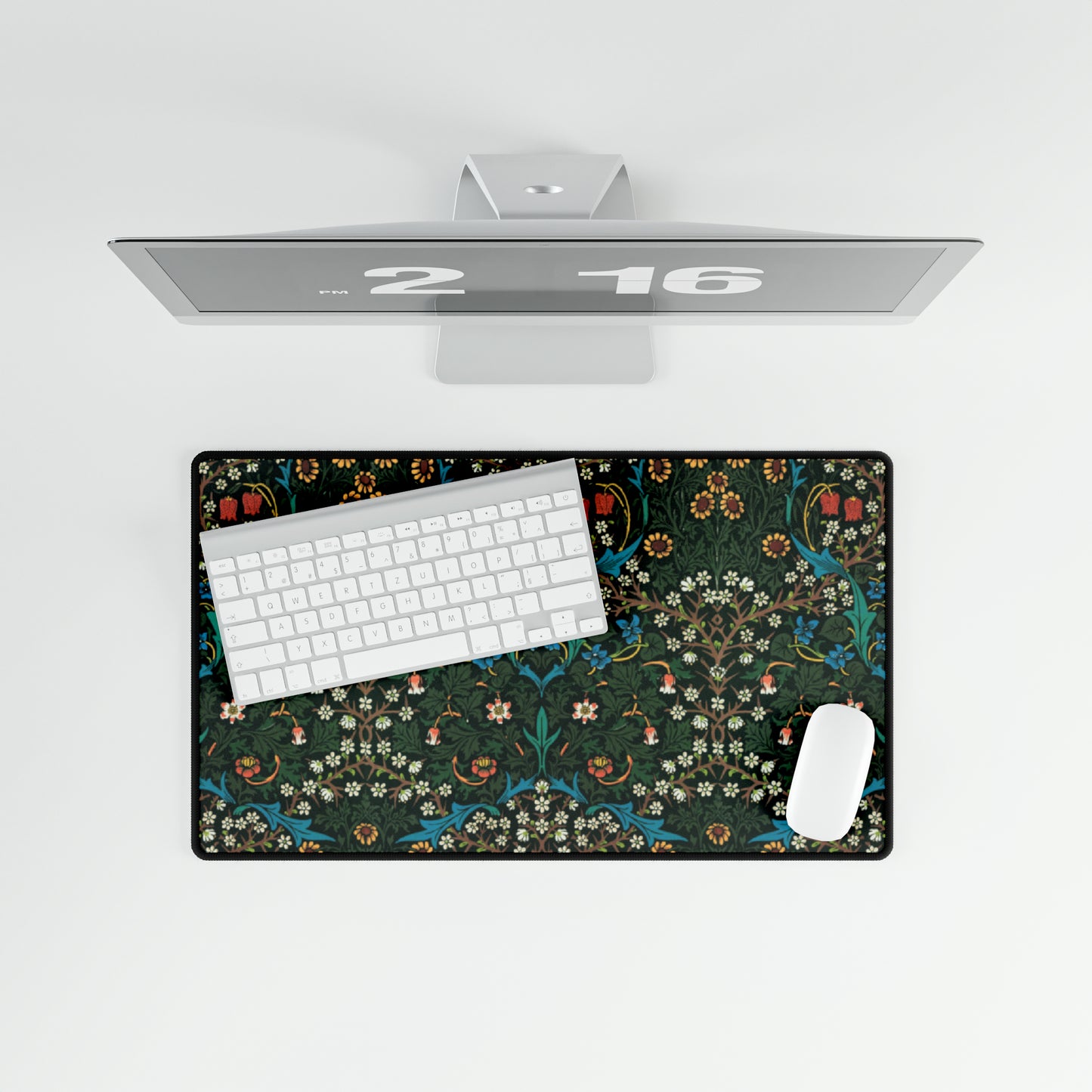 A rectangular desk mat with a floral tulip pattern in red, black, and gray, placed on a desk under a white mouse pad and a silver monitor, against a white background.