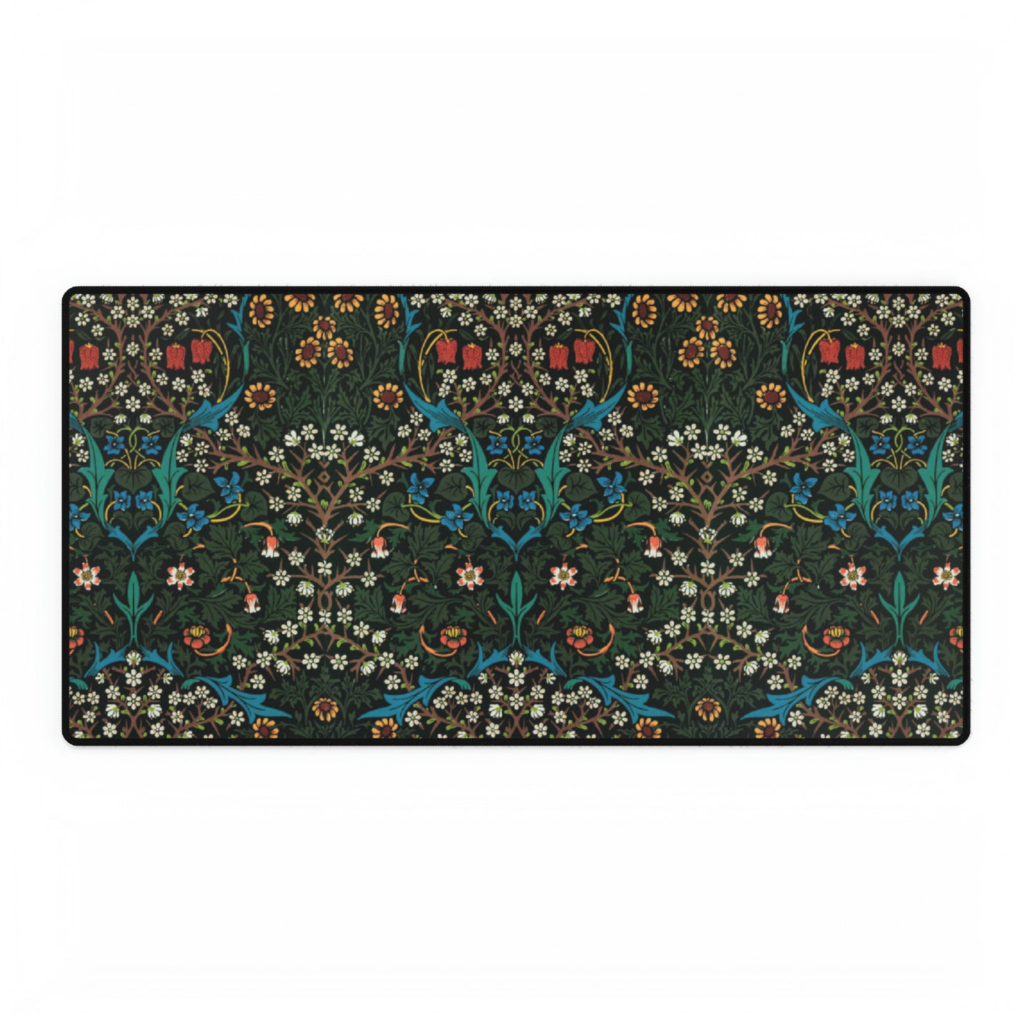 A rectangular desk mat with a William Morris & Co floral tulip pattern in red, black, and green, placed under a white desk lamp and a white keyboard.