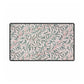Floral patterned rug with green leaves and red stems on a light background