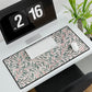 Floral patterned desk mat on a desk with a computer and plants in the background