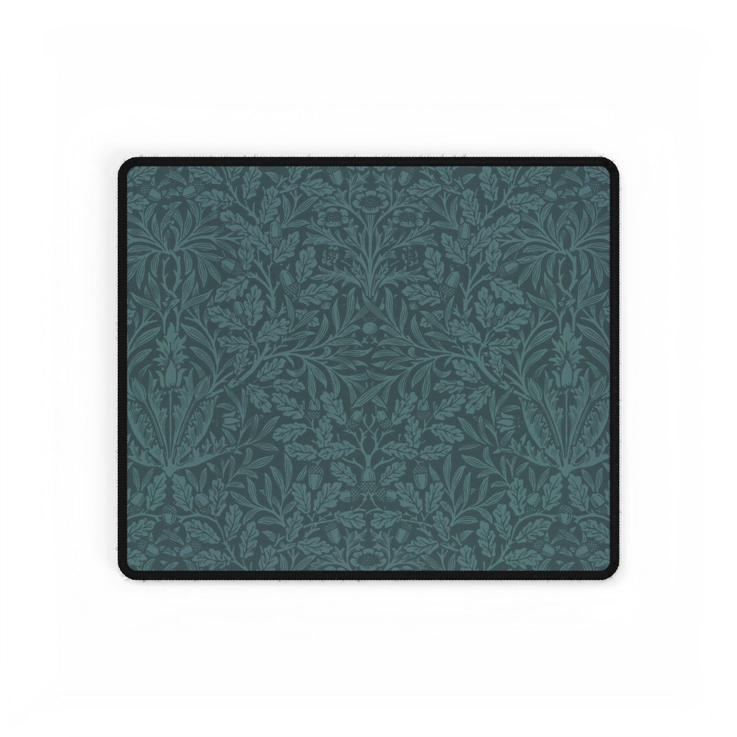 A rectangular desk mat with a teal background and an intricate floral pattern of acorns and oak leaves.