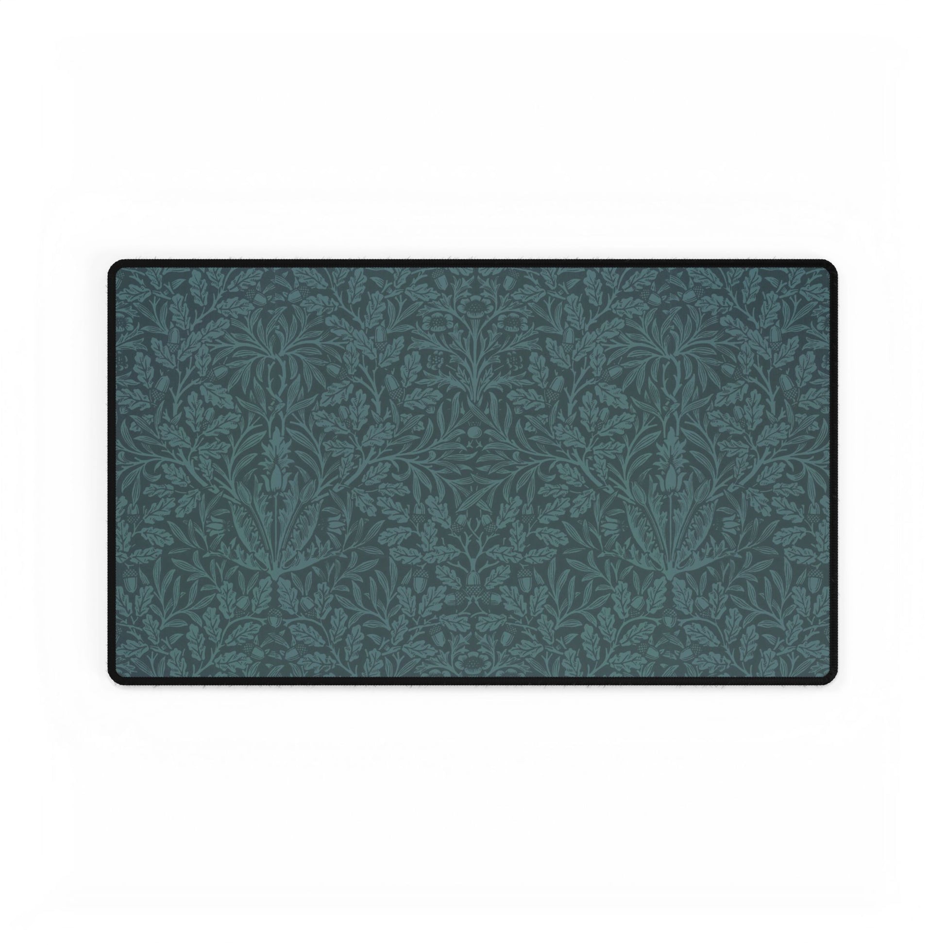 A rectangular desk mat with a teal background and an intricate floral pattern of acorns and oak leaves.