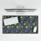 A desk mat with a William Morris & Co floral pattern, featuring a mouse pad on top. The desk mat has a non-slip base and is placed under a shelf with a computer monitor and a keyboard.