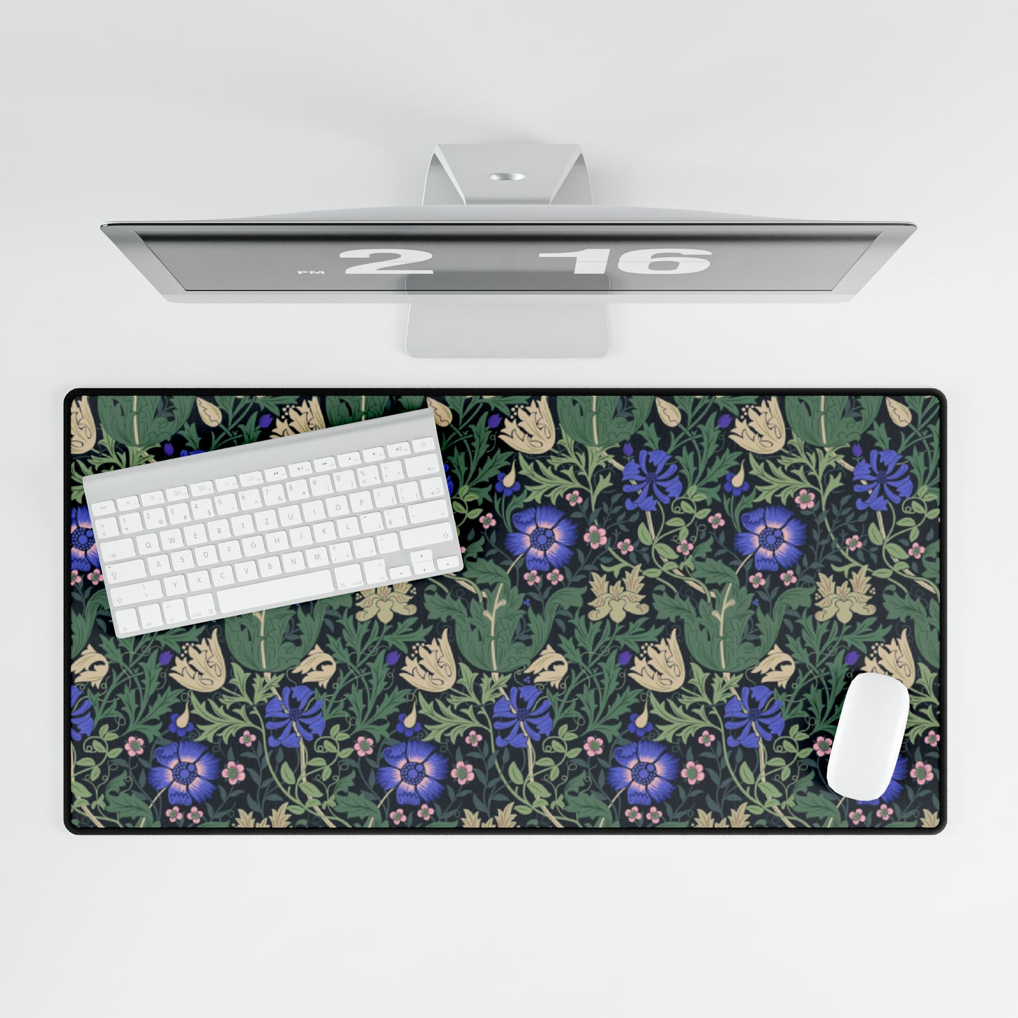 A desk mat with a William Morris & Co floral pattern, featuring a mouse pad on top. The desk mat has a non-slip base and is placed under a shelf with a computer monitor and a keyboard.