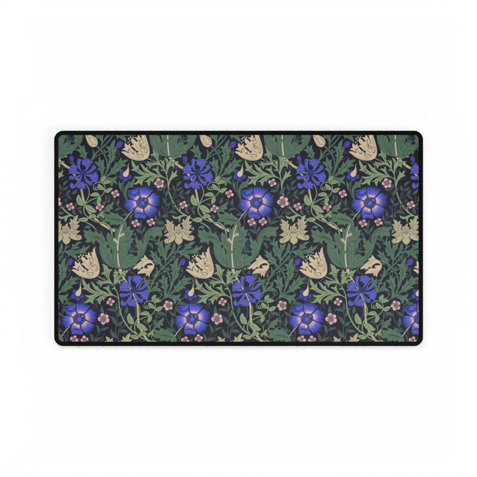 A desk mat with a William Morris & Co floral pattern, featuring a mouse pad on top. The desk mat has a non-slip base and is placed under a shelf with a computer monitor and a keyboard.
