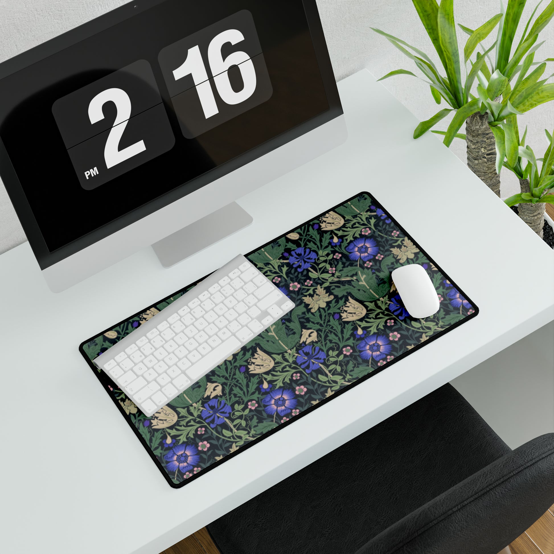 A desk mat with a William Morris & Co floral pattern, featuring a mouse pad on top. The desk mat has a non-slip base and is placed under a shelf with a computer monitor and a keyboard.