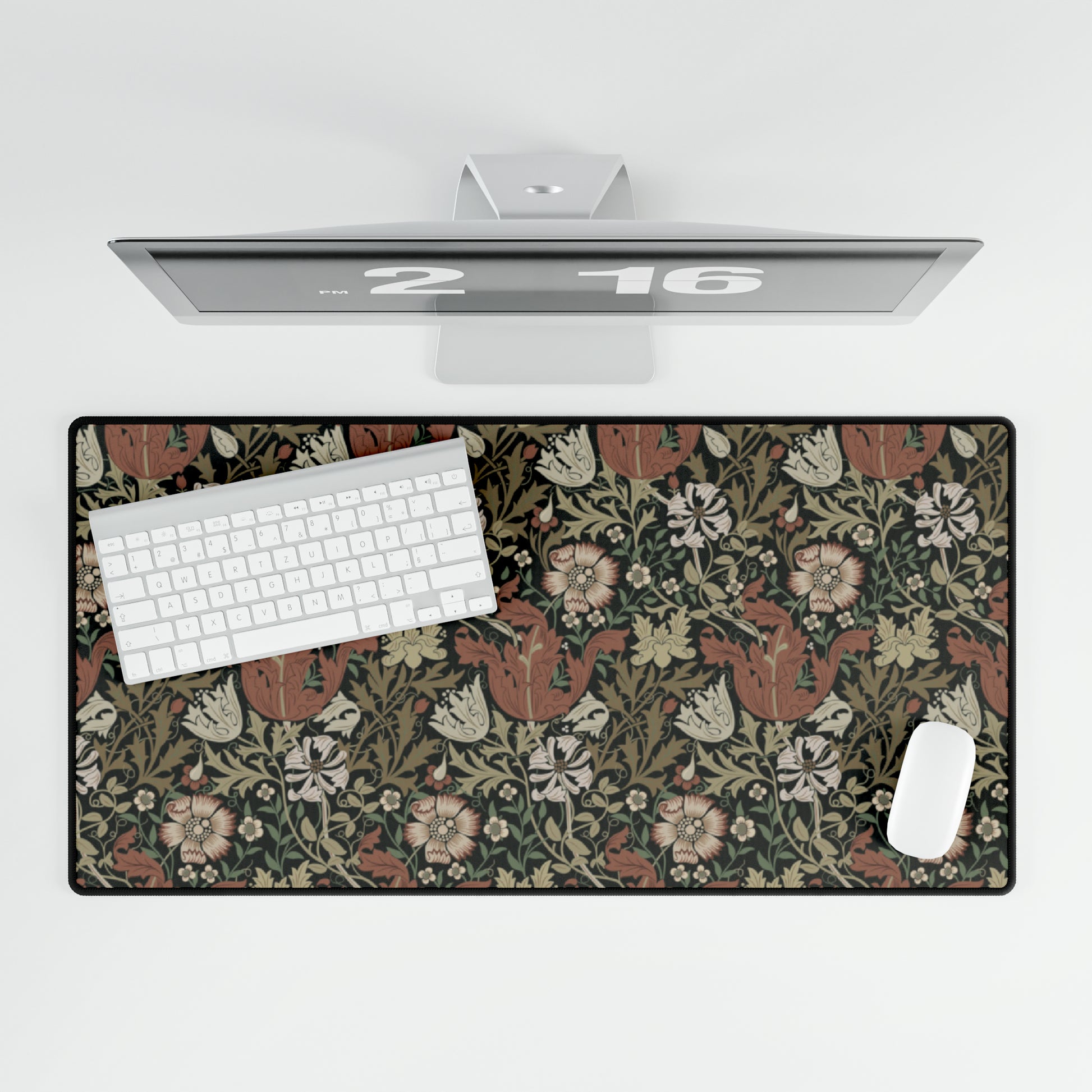 A large, rectangular neoprene desk mat with a William Morris & Co floral pattern, displayed under a computer monitor and keyboard, illustrating its use in a workspace.