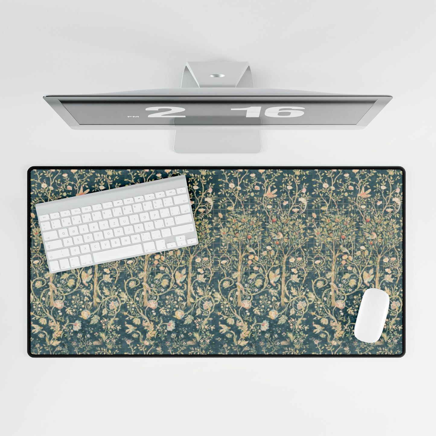 A large desk mat with a floral William Morris & Co pattern in evergreen teal colours, displayed on a desk with a keyboard and mouse.