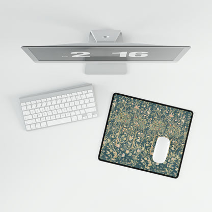 A large desk mat with a floral pattern in evergreen teal colors, displayed on a desk with a keyboard and mouse.