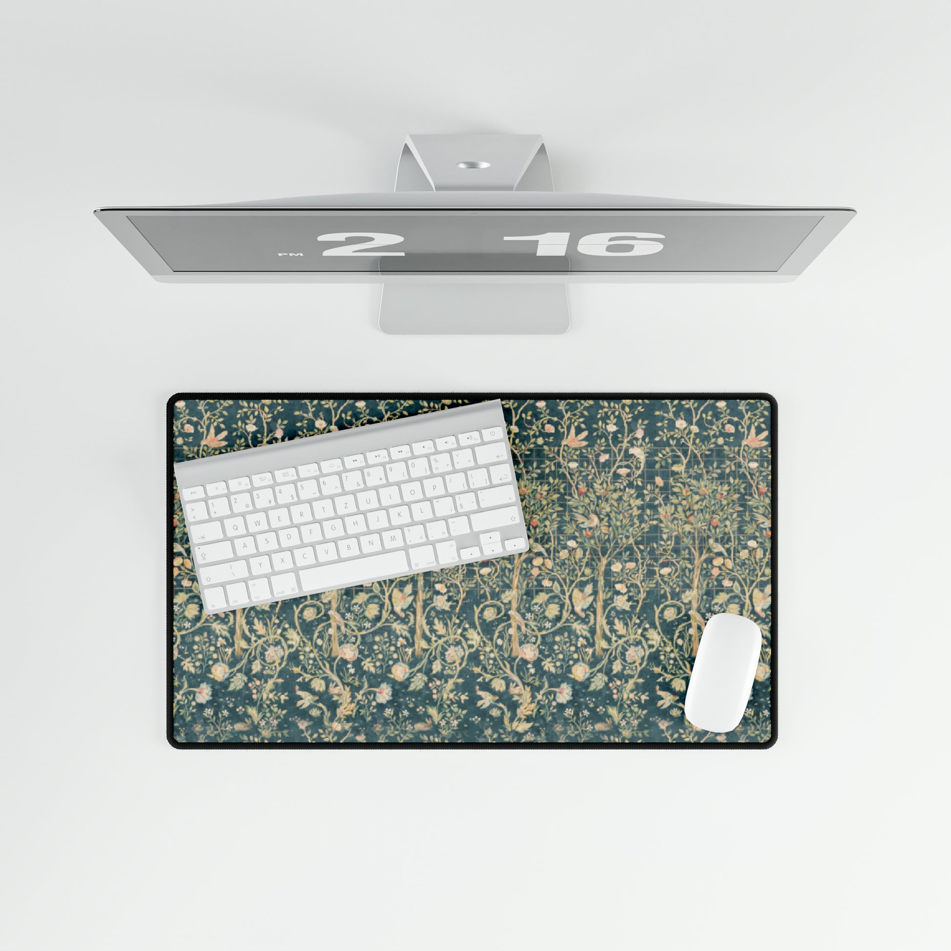 A large desk mat with a floral pattern in evergreen teal colors, displayed on a desk with a keyboard and mouse.