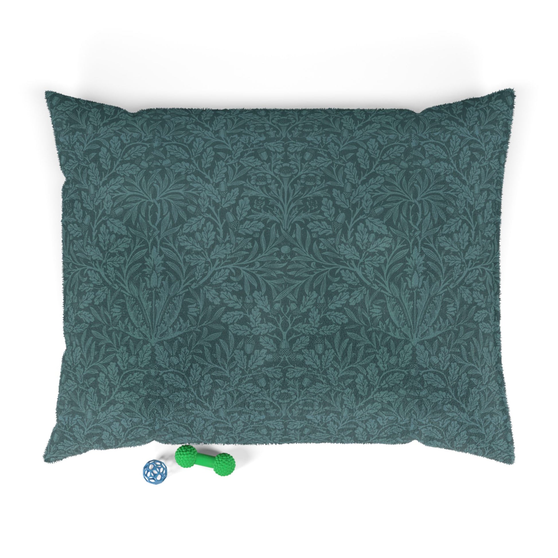 Green patterned dog bed pillow on a white background with two small toys at the bottom.