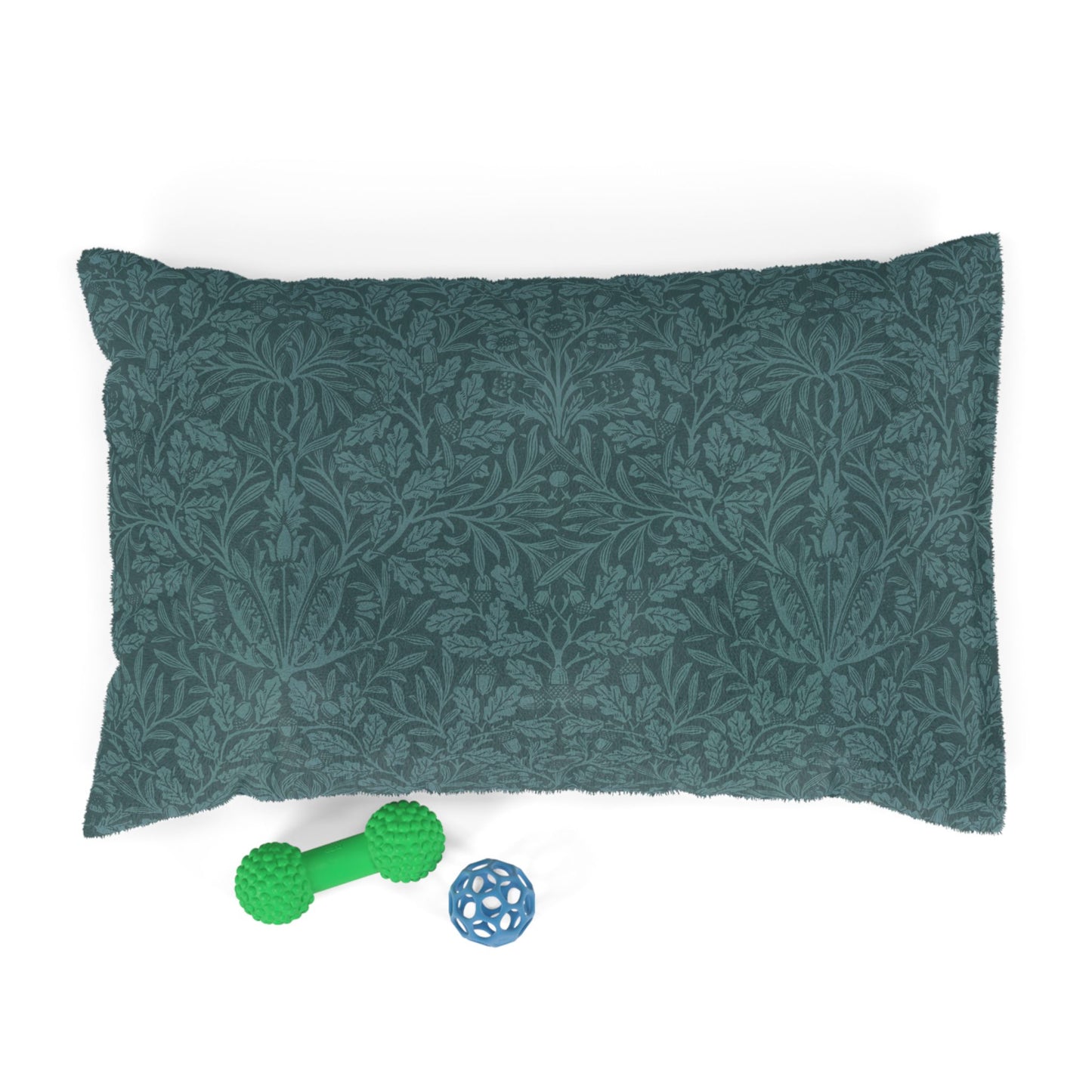 Green patterned pillow with a green rubber dog toy and blue ball on a white background