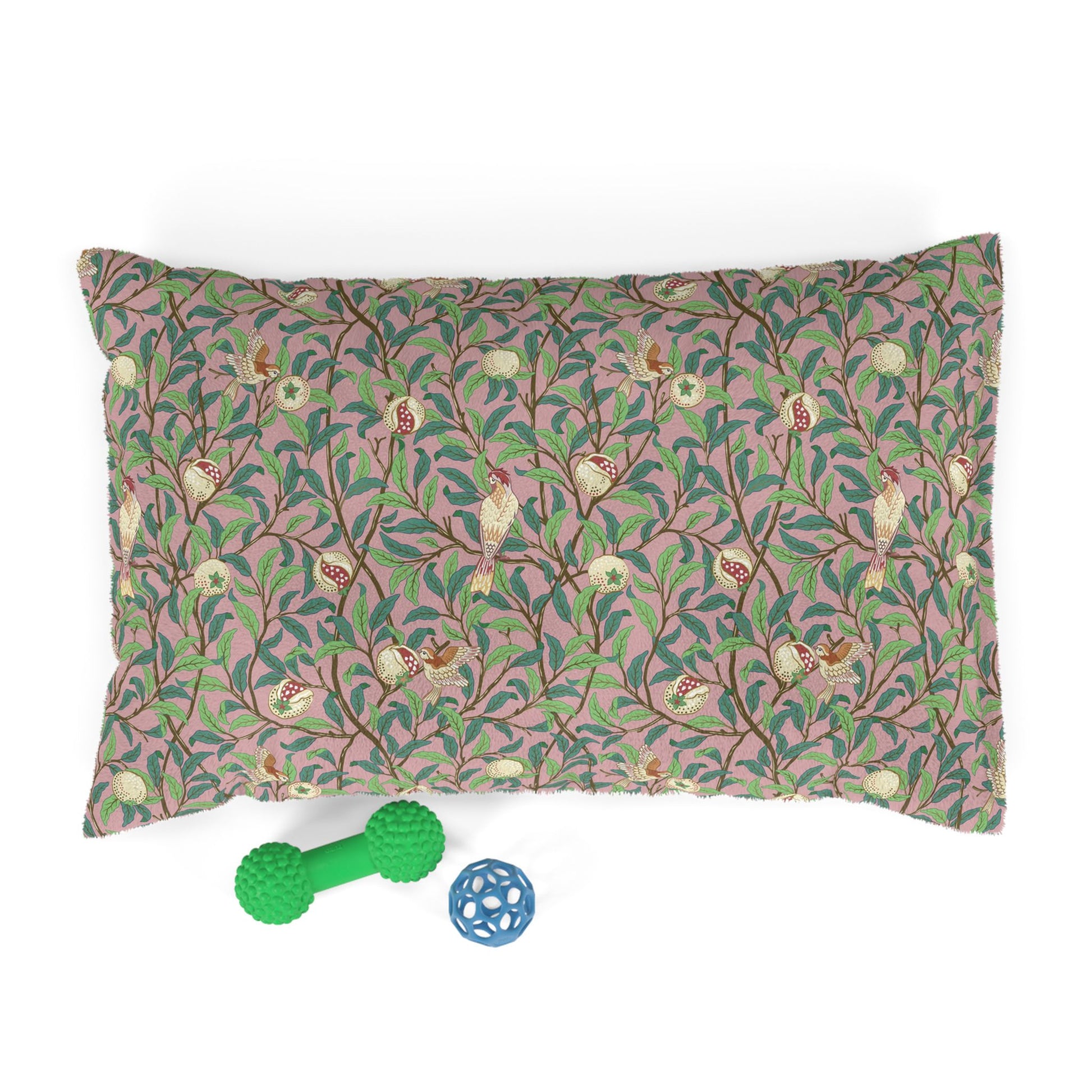 Decorative pillow with floral pattern and two pet toys on a white background