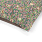 Fabric with a nature-themed pattern featuring birds, leaves, and flowers on a pink background.
