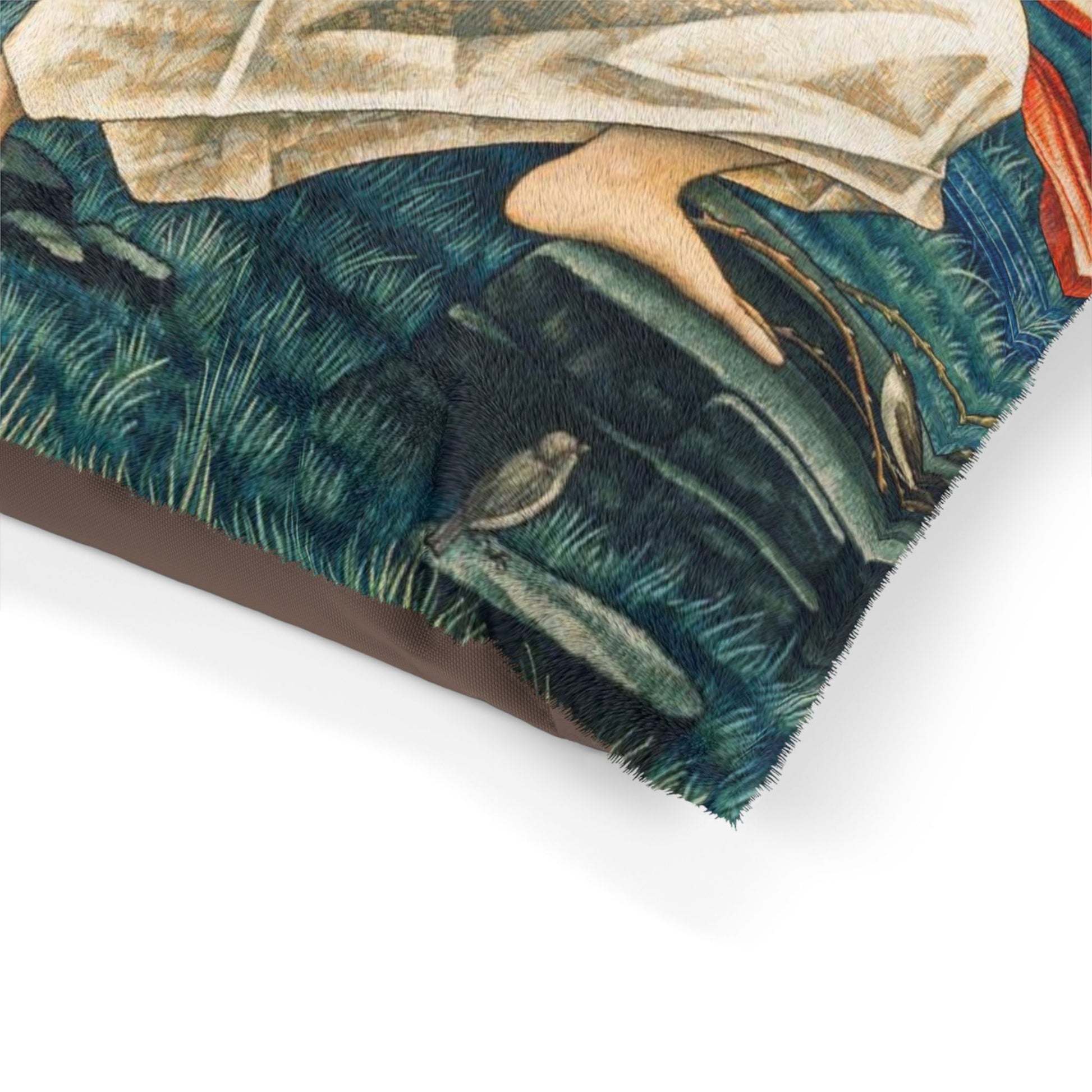Close-up of a dog bed pillow with a person sitting on grass, surrounded by nature.