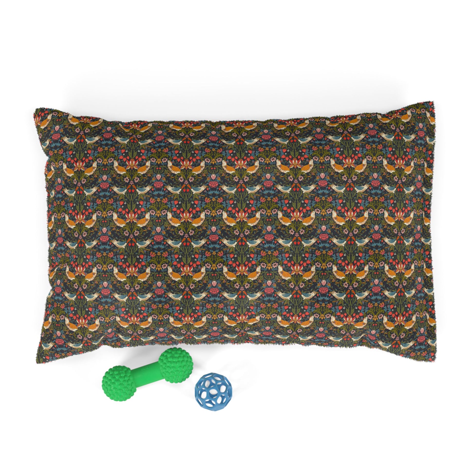 Decorative pillow with a pattern, green rubber dog toy, and blue ball on a white background