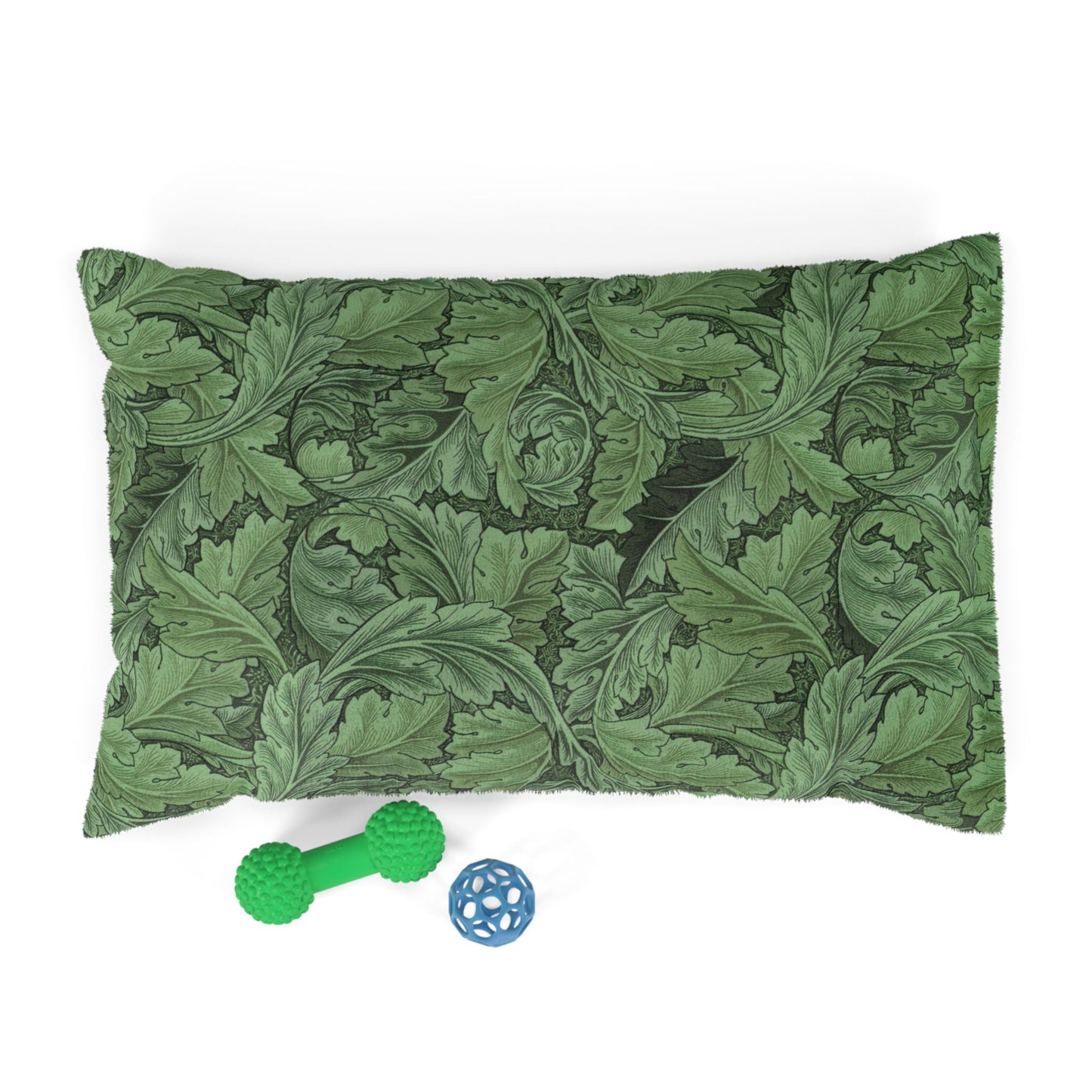 Green leaf-patterned pillow with a green rubber dog toy and blue ball on a white background