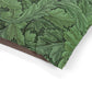 Close-up of green leafy patterned fabric with a brown border on a white background