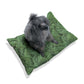 Dog sitting on a green leaf-patterned cushion against a white background