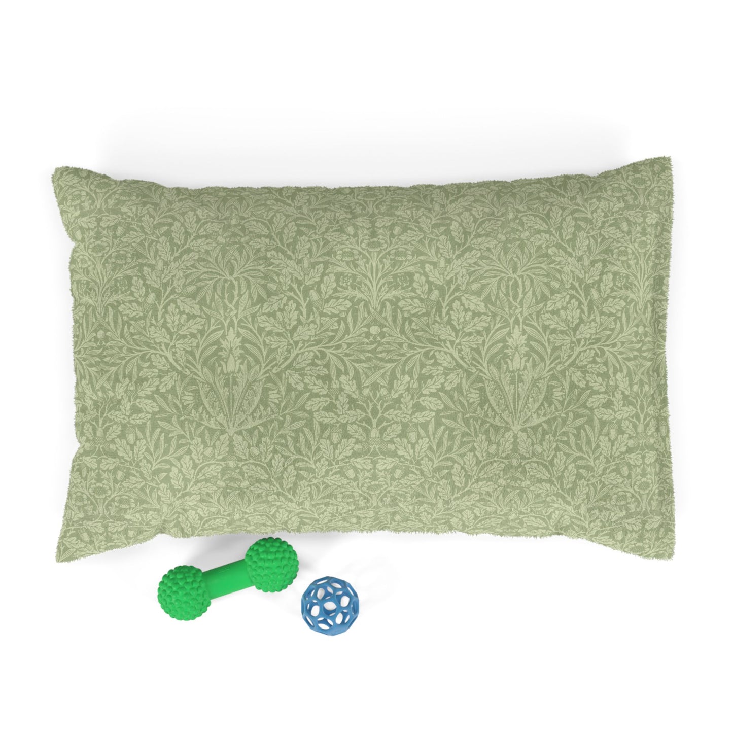 Green patterned pillow with a green rubber dog toy and blue ball on a white background