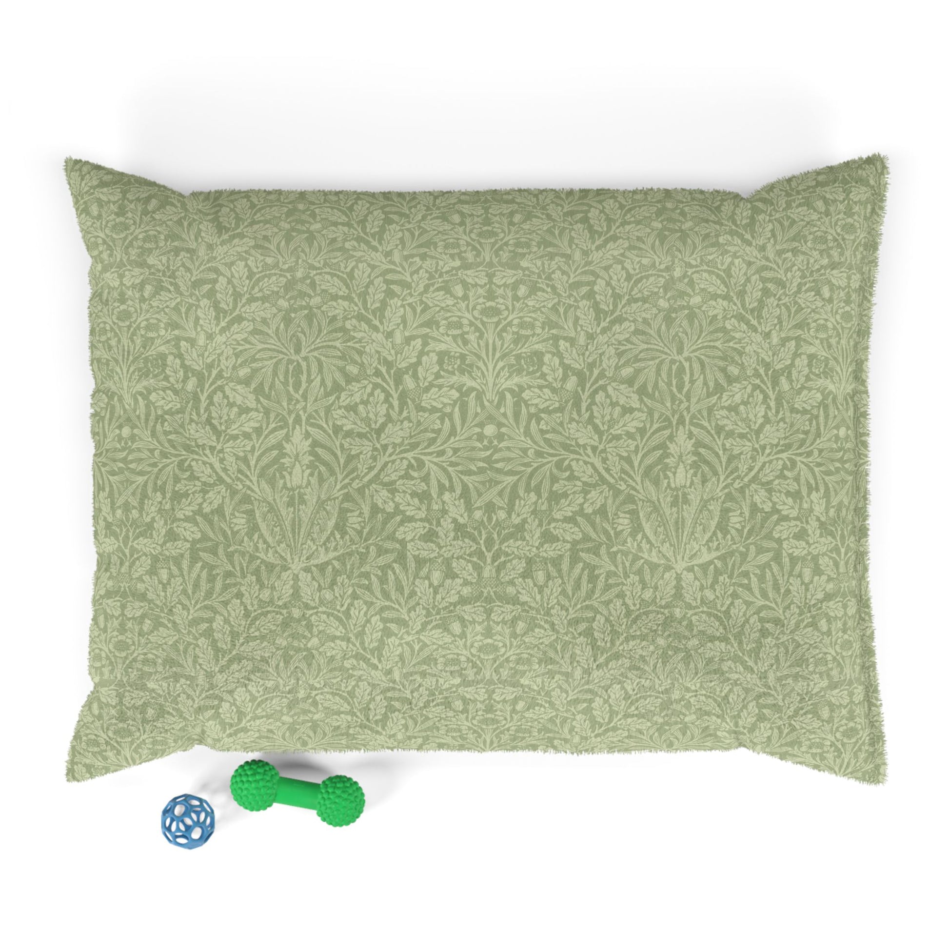Green patterned pillow on a white background with a green dog toy below.