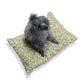 Dog sitting on a William Morris & Co patterned dog bed with a white background