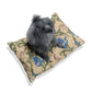 Dog sitting on a William Morris & Co decorative pillow with floral patterns on a white background