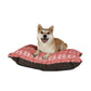Dog sitting on a red and white patterned dog bed with a brown border.