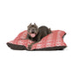 Dog lying on a red and white patterned dog bed with a white background