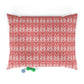 Red and white patterned pillow with two dog toys on a white background