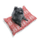 Dog sitting on a red floral pillow against a white background