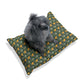 Dog sitting on a green and yellow patterned pillow against a white background