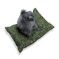 Dog sitting on a green patterned pillow against a white background