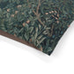 Close-up of a floral patterned fabric with green leaves and brown branches on a white background