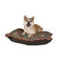 Dog sitting on a decorative dog bed with a nature-themed pattern on a white background