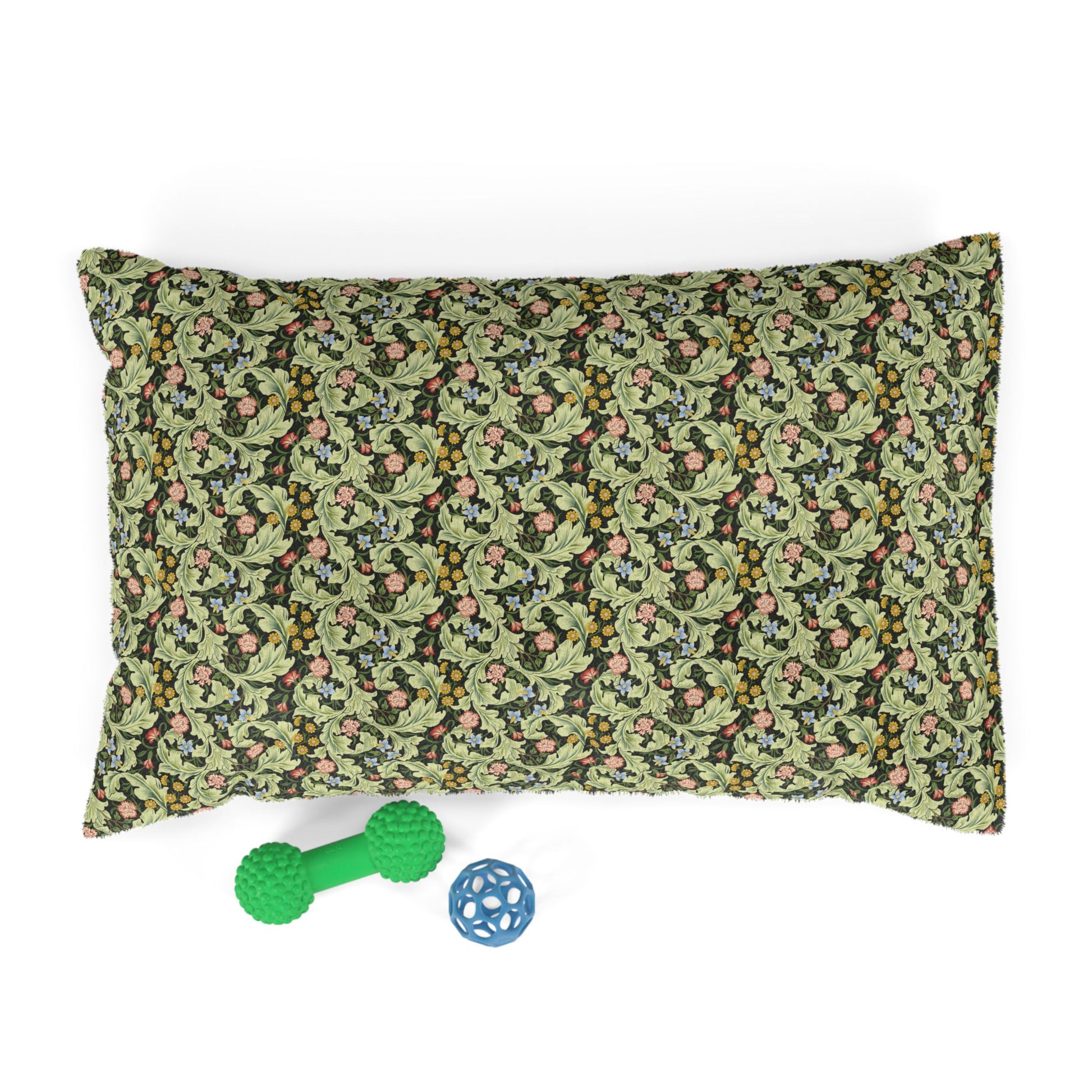 Floral-patterned pillow with a green dog toy and blue ball on a white background