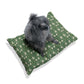 Dog sitting on a green William Morris & Co floral-patterned cushion against a white background