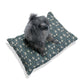 Gray poodle sitting on a William Morris & Co patterned dog bed against a white background