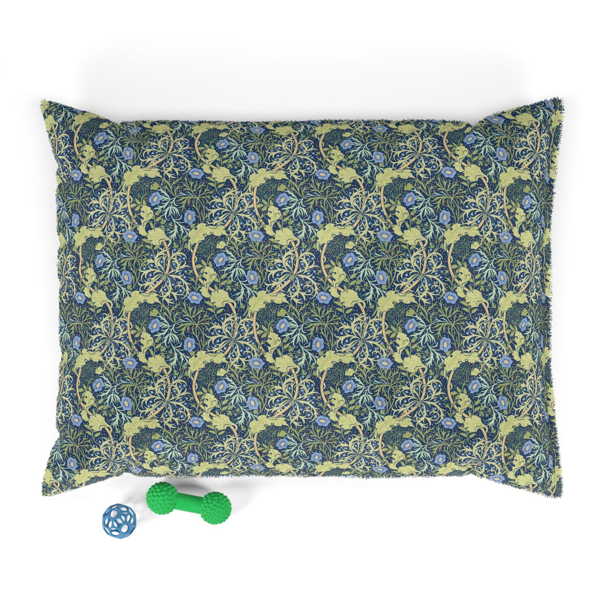 Floral patterned pillow with a green dog toy on a white background