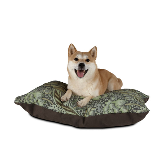 Dog sitting on a William Morris & Co patterned dog bed with a white background