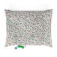 Floral patterned pillow with a green dog toy on a white background