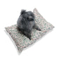 Dog sitting on a patterned dog bed with a white background