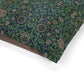Dog sitting on a William Morris & Co patterned green cushion against a white background