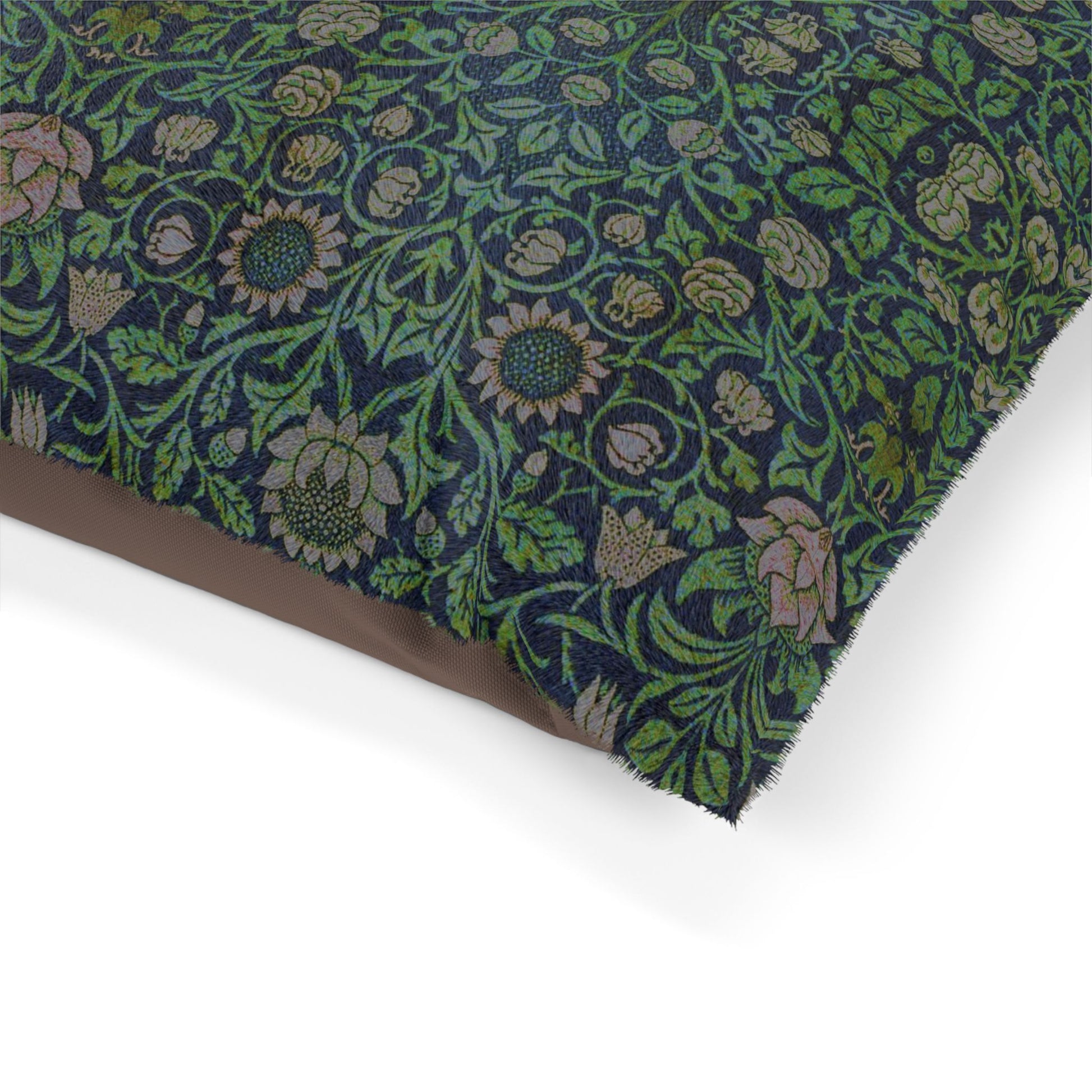Dog sitting on a William Morris & Co patterned green cushion against a white background