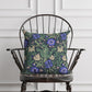 A square-shaped faux suede cushion with a floral William Morris & Co pattern featuring blue flowers and green leaves on a dark background called Compton.