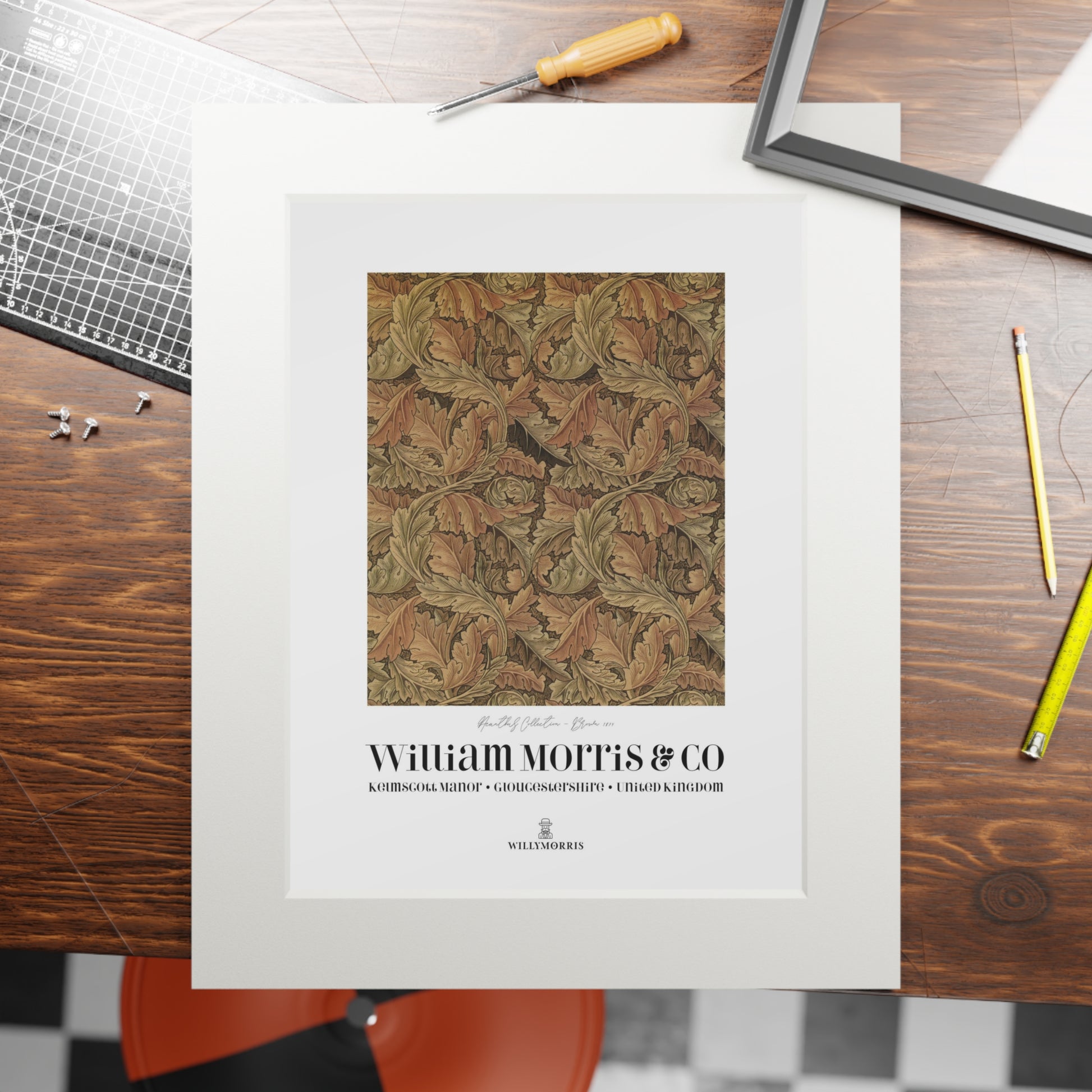 Framed textile pattern with 'William Morris & Co' branding on a wooden table.