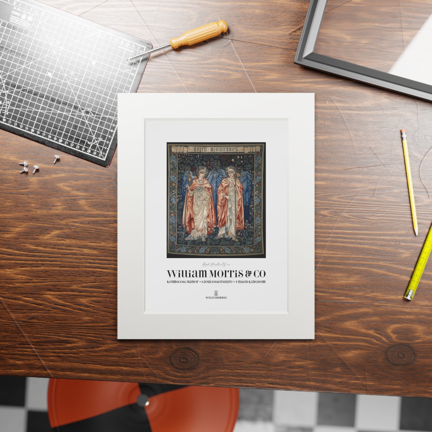 Framed artwork on a wooden table with tools and a chair in the background